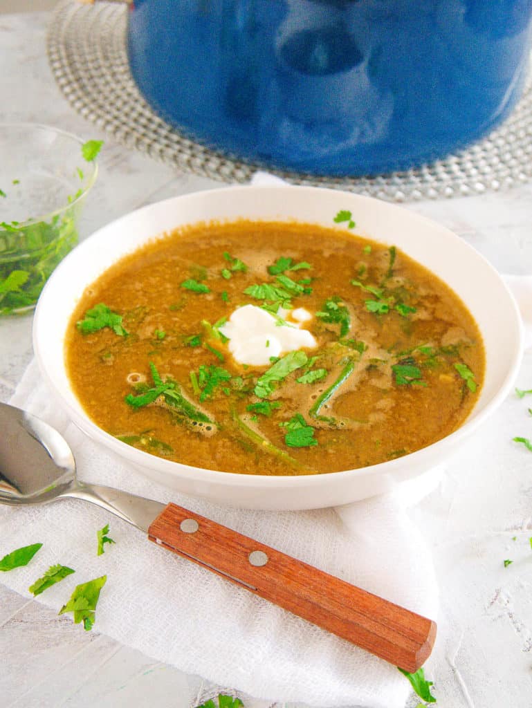 lebanese lentil soup with spinach, served in a white bowl with cilantro on top