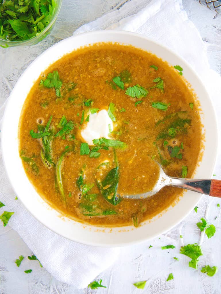 lebanese lentil soup with spinach, served in a white bowl with cilantro on top