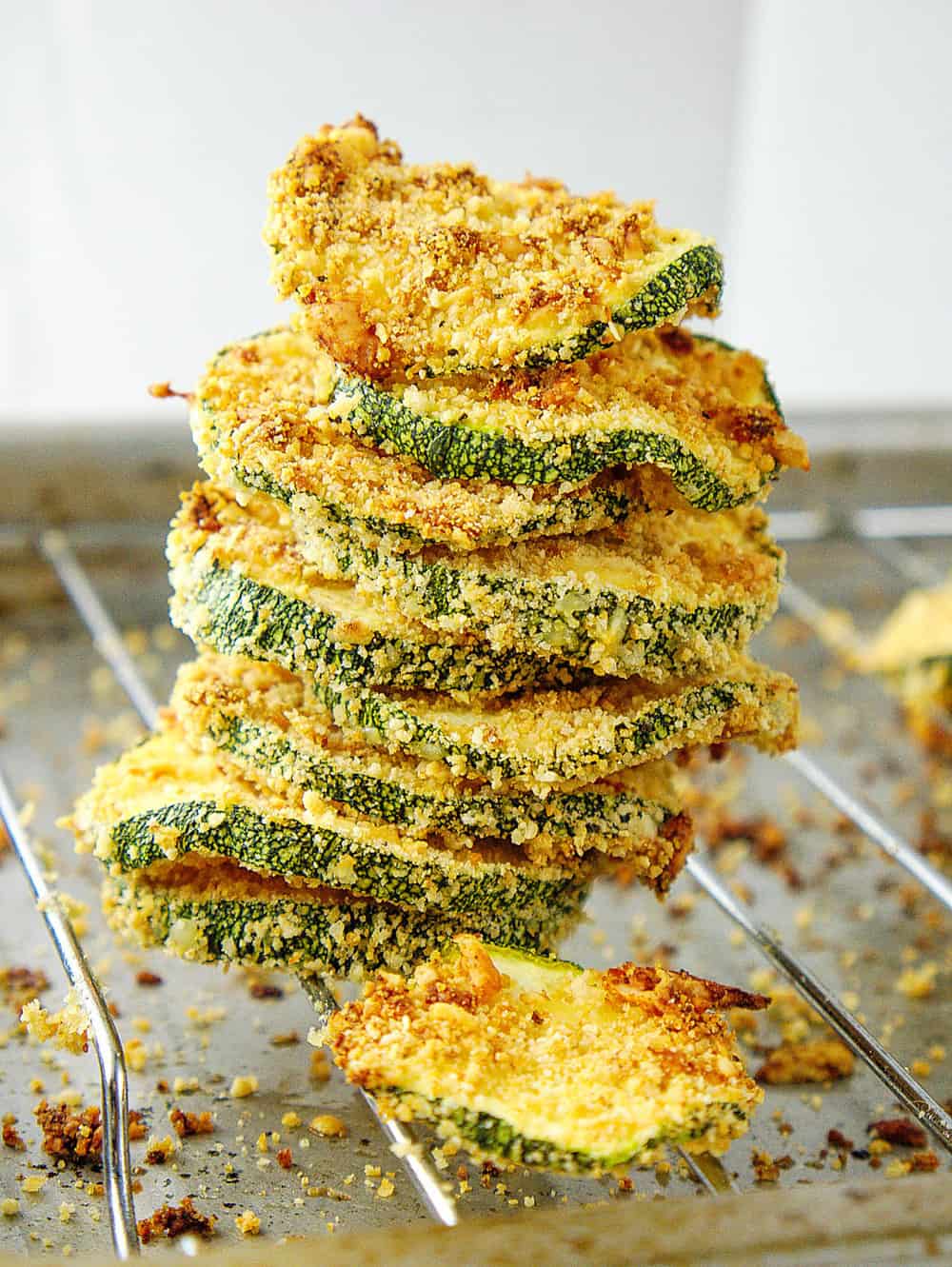 baked and crispy courgette chips with parmesan, stacked on an oven rack