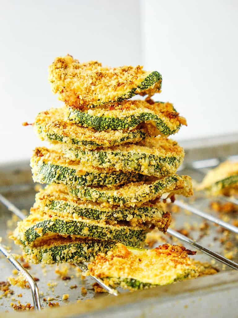 baked and crispy courgette chips with parmesan, stacked on an oven rack