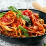 Vegetarian Spaghetti Sauce with whole wheat pasta, served in a black bowl with basil on top