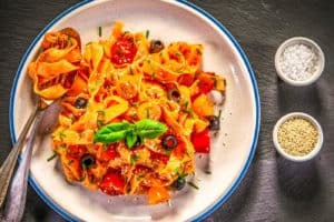homemade tagliatelle with fresh tomatoes and parmesan on wood background