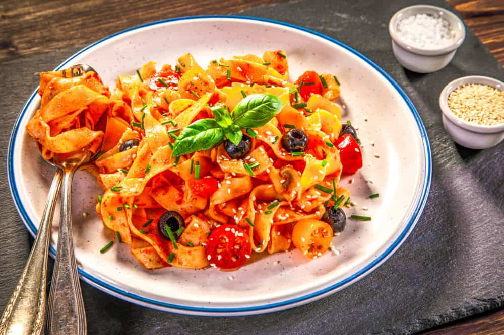 homemade tagliatelle with fresh tomatoes and parmesan on wood background