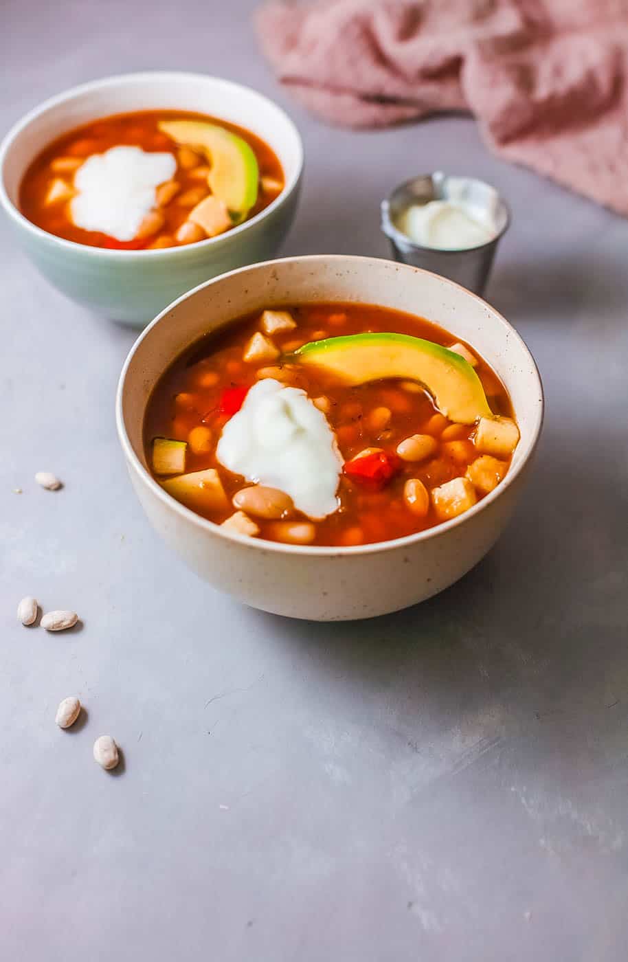 vegan white bean soup served with avocado and greek yogurt in a white bowl