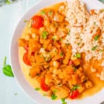 ،ernut squash and chickpea curry, served on a white plate with couscous on the side