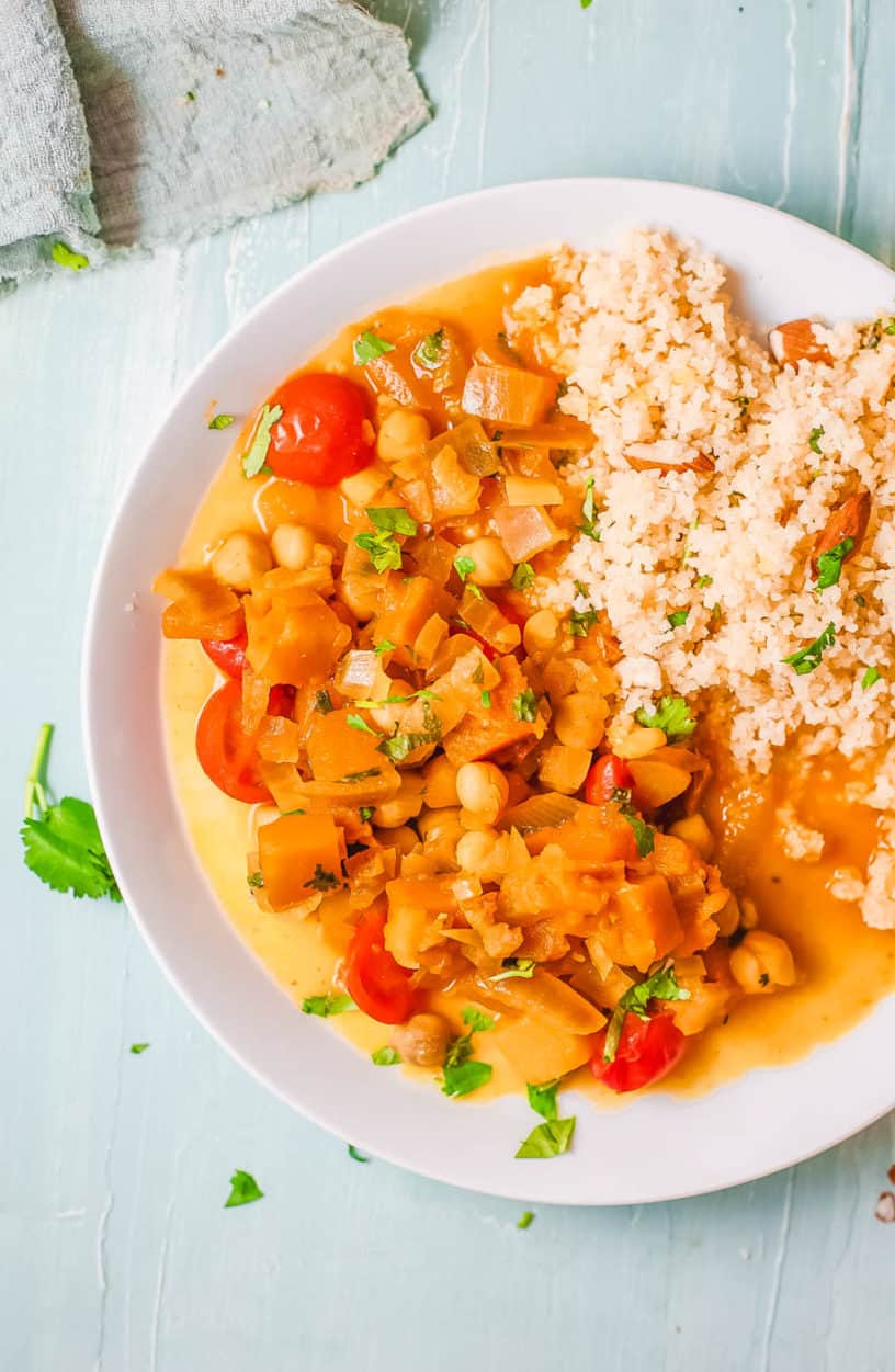 butternut squash and chickpea curry, served on a white plate with couscous on the side