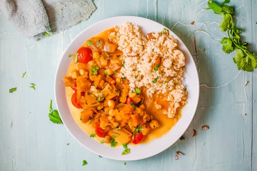 butternut squash and chickpea curry, served on a white plate with couscous on the side