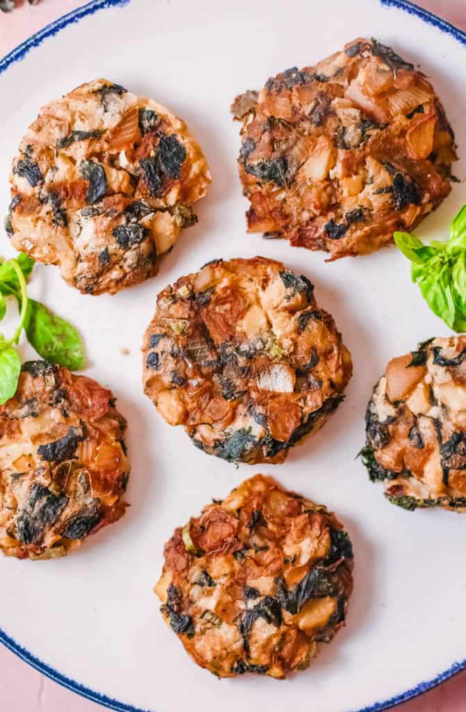 mashed ،ato fritters with onions and kale, served on a white plate, top view