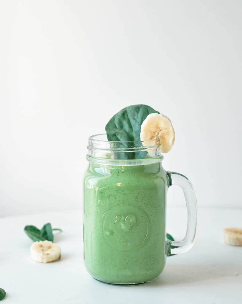spinach banana smoothie with peanut butter served in a glass mason jar