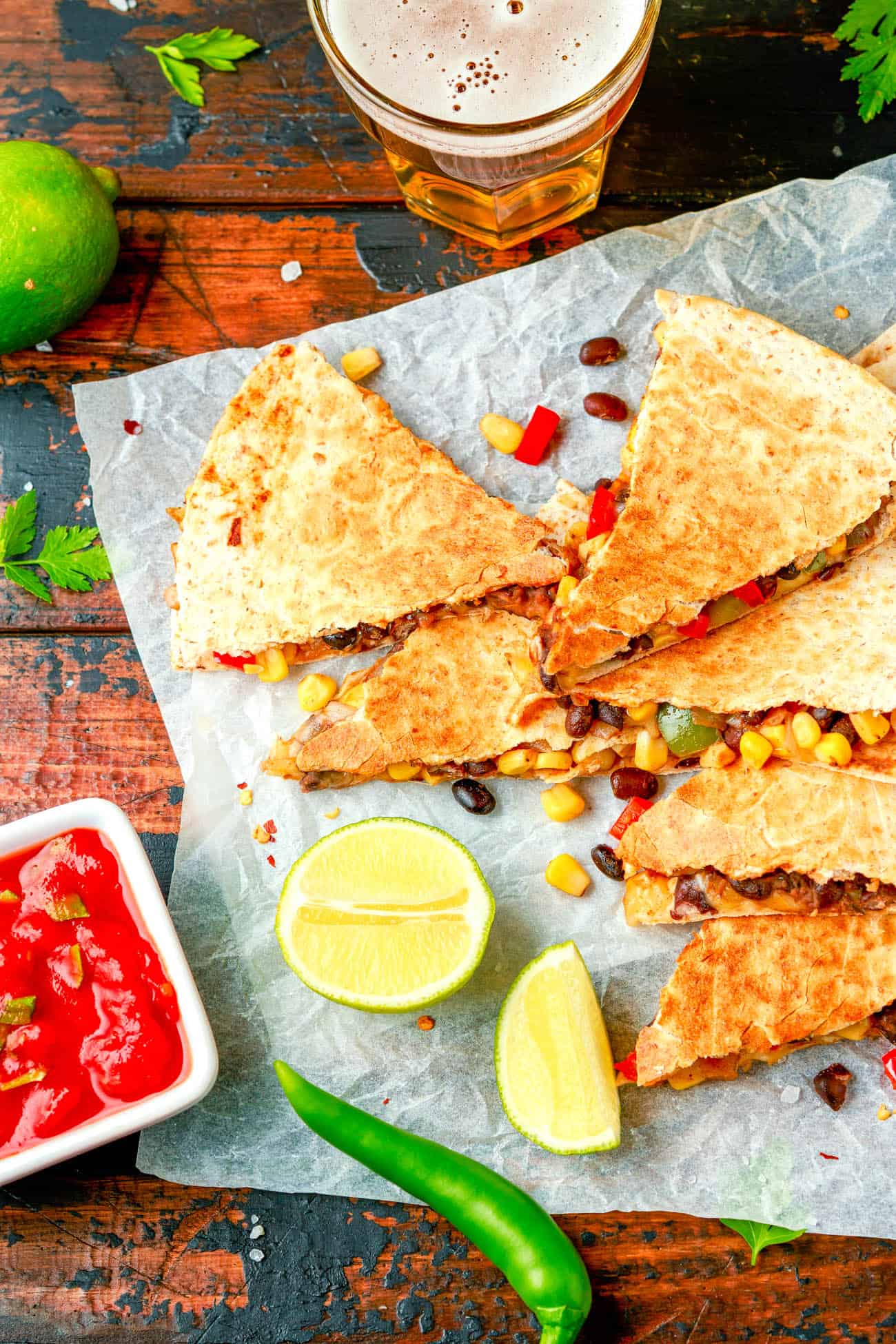 veggie quesadilla recipe -  black beans tomato corn quesadilla served with cold ، salsa and yogurt dip sause on dark wooden background.