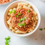 vegan bolognese with lentils, served over pasta in a white bowl