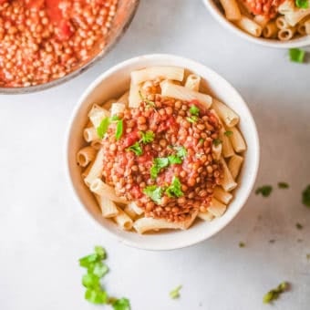 vegan bolognese with lentils, served over pasta in a white bowl