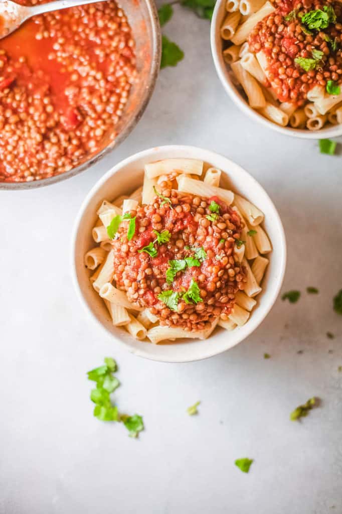 vegan bolognese with lentils, served over pasta in a white bowl