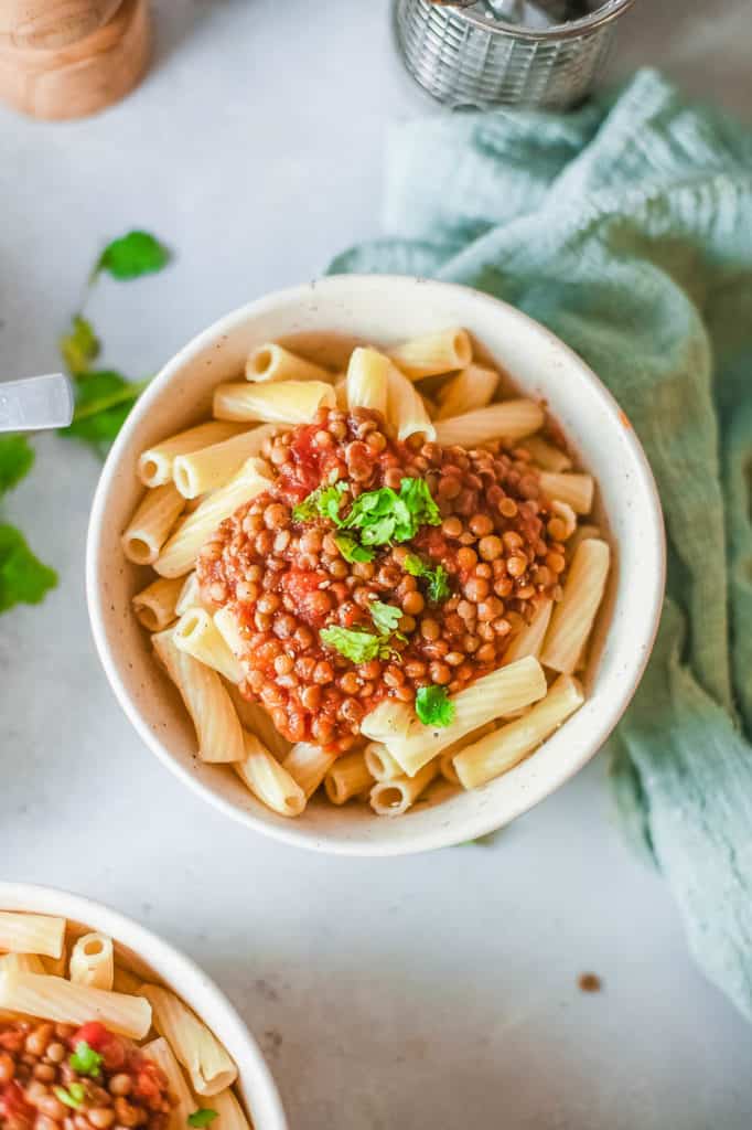 vegan bolognese with lentils, served over pasta in a white bowl - 30 minute vegetarian meals