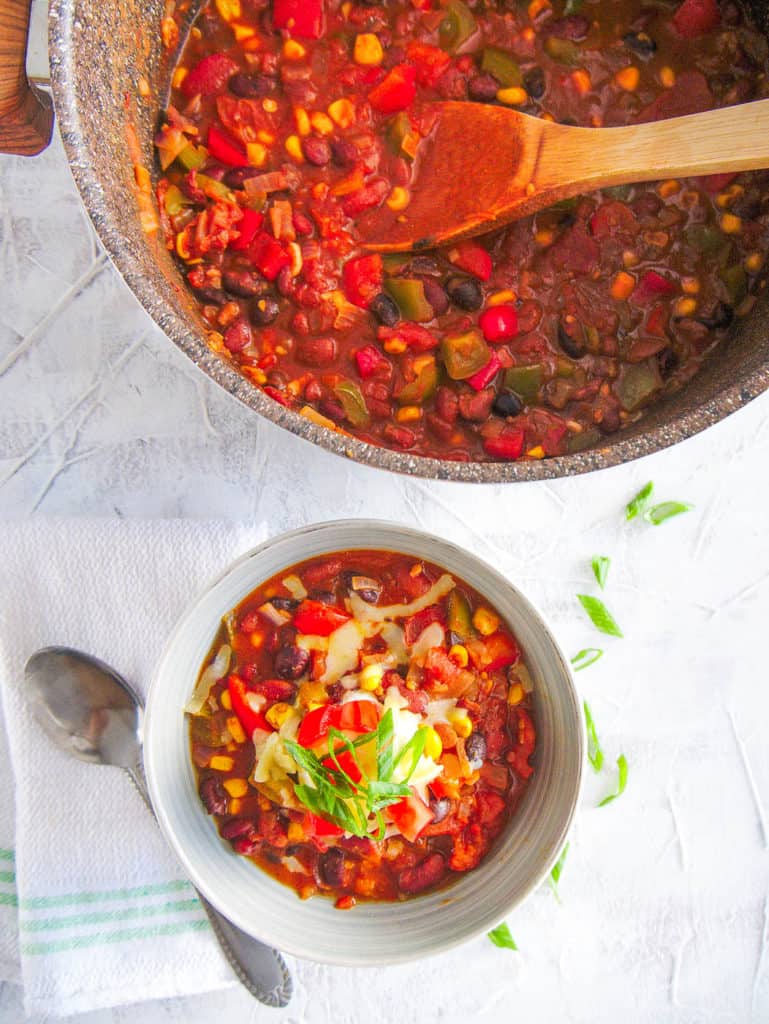 The Best Instant Pot Vegetarian Chili served in a white bowl topped with green onions and cheese