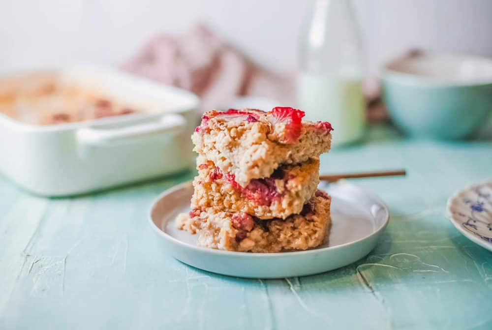 cut squares of vegan baked oatmeal topped with berries, served on a white plate