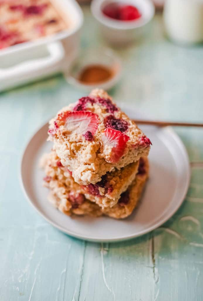 cut squares of vegan baked oatmeal topped with berries, served on a white plate