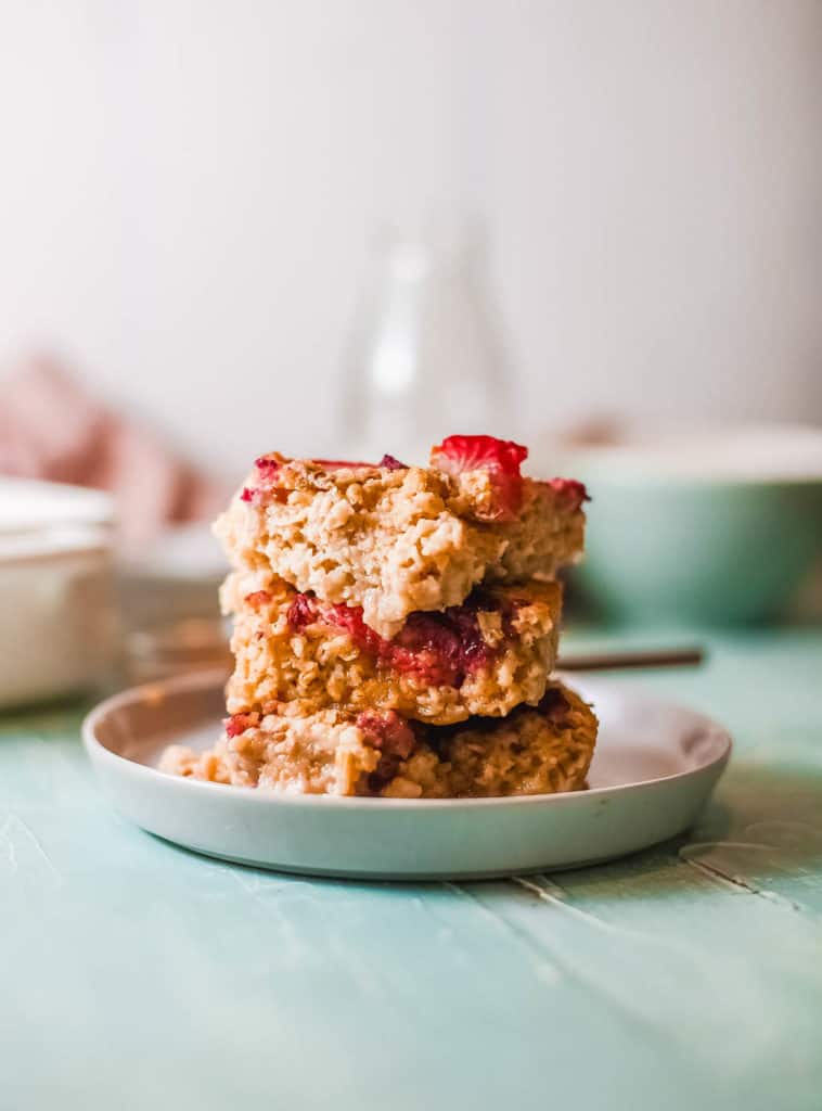 cut squares of vegan baked oatmeal topped with berries, served on a white plate