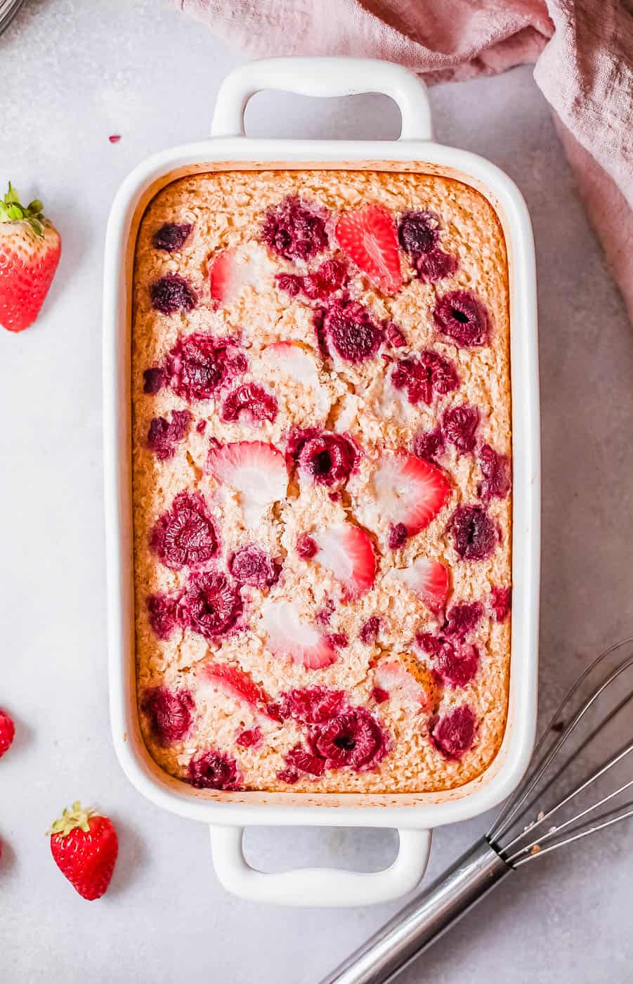 vegan baked oatmeal topped with berries in a casserole dish, fresh out of the oven