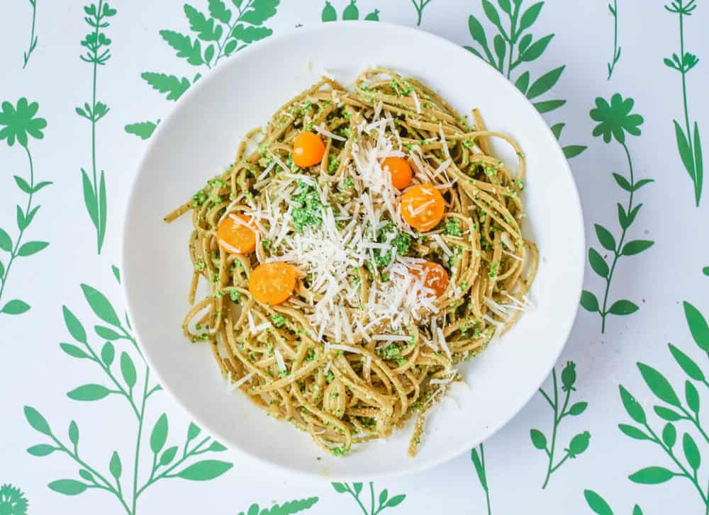 vegetarian pesto pasta with spinach and herbs, served on a white plate