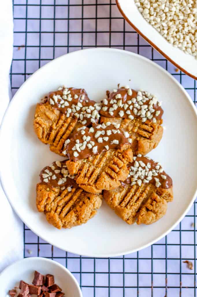 Keto Peanut Butter Cookies dipped in chocolate and nuts, on white plate