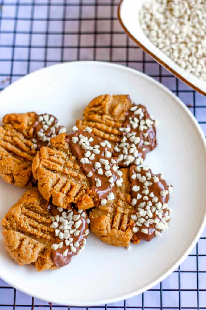 Keto Peanut Butter Cookies dipped in chocolate and nuts, on white plate