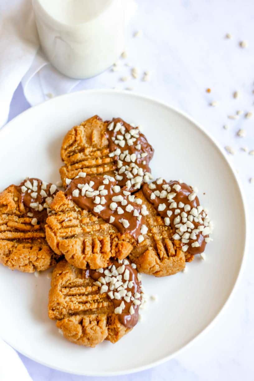 Keto Peanut Butter Cookies dipped in chocolate and nuts, on white plate