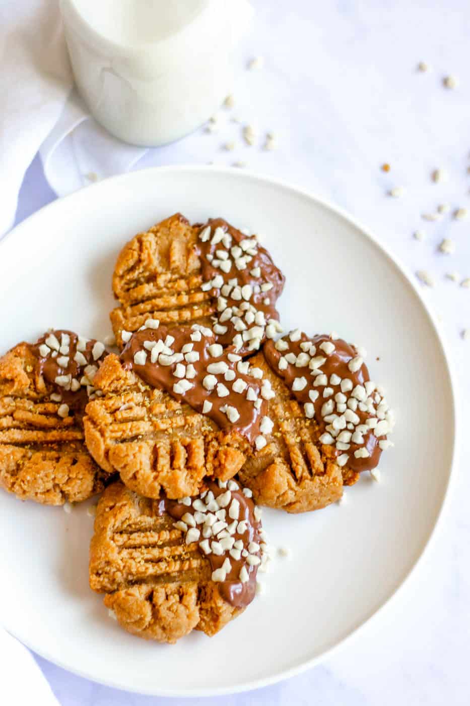 Almond Flour Peanut Butter Cookies dipped in chocolate and nuts, on white plate.