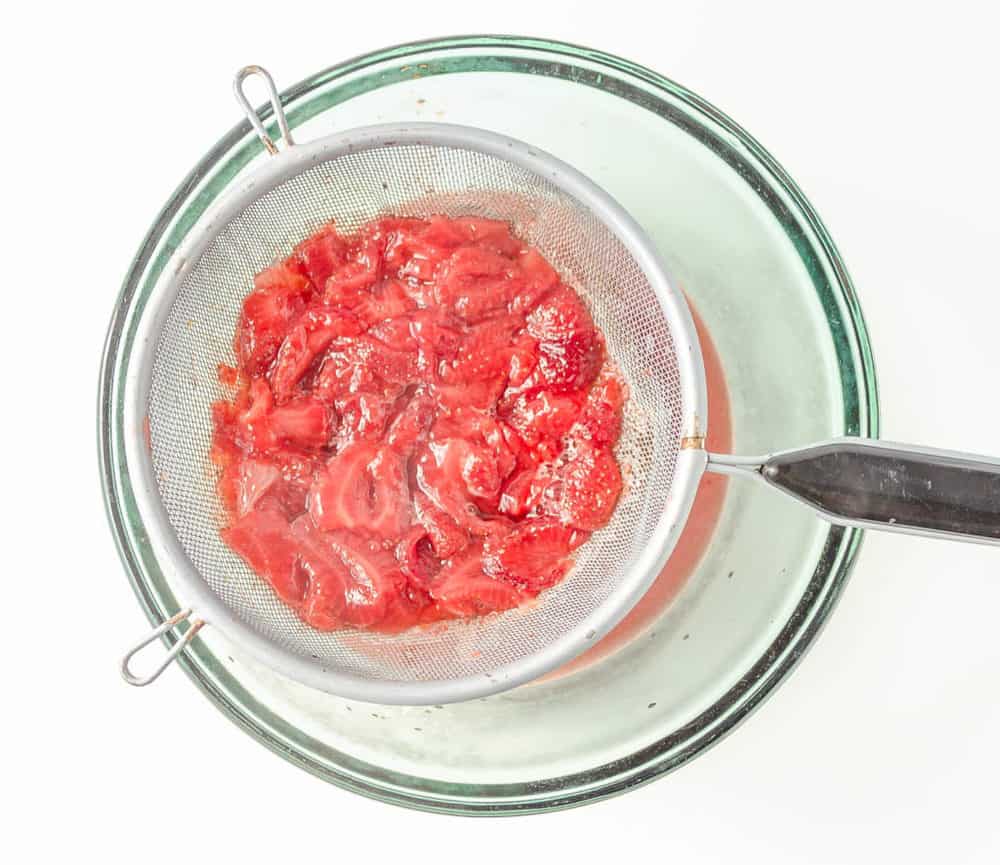 straining strawberries to make syrup