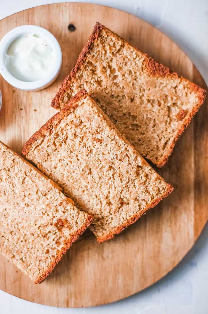 gluten free bread served on a wooden board with a side of jam and butter