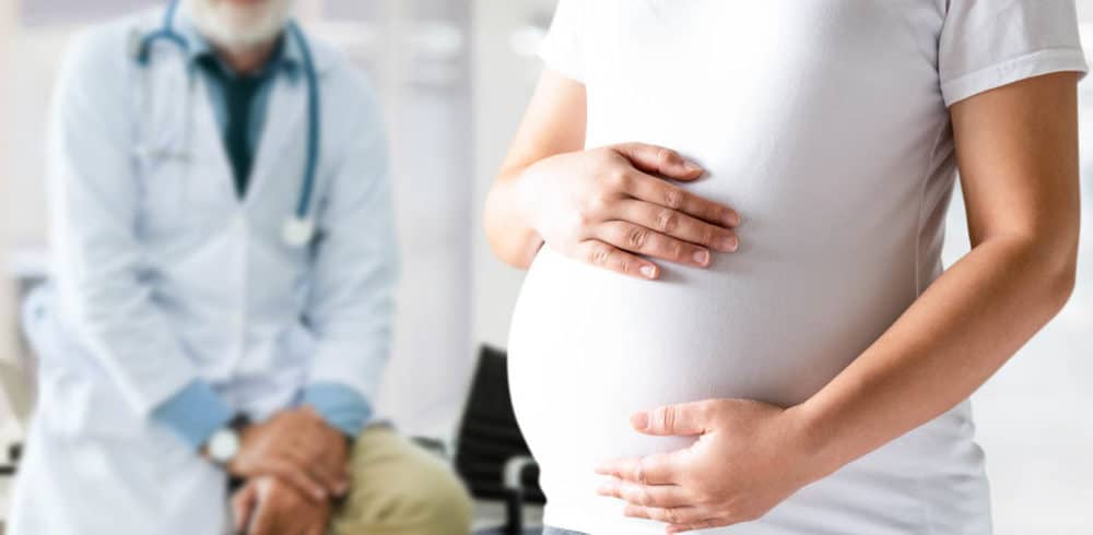 Happy pregnant woman visit gynecologist doctor at hospital or medical clinic for pregnancy consultant. Doctor examine pregnant belly for baby and mother healthcare check up. Gynecology concept.