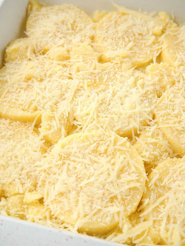 Parmesan cheese and polenta slices layered in a baking dish.