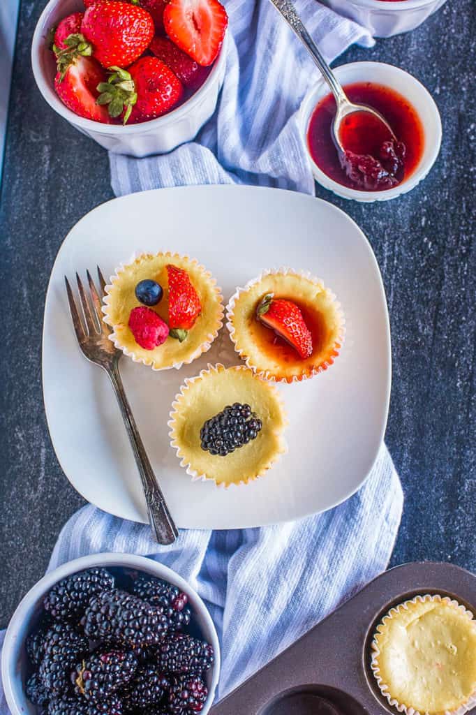 cheesecake bites topped with fresh fruit on a white plate