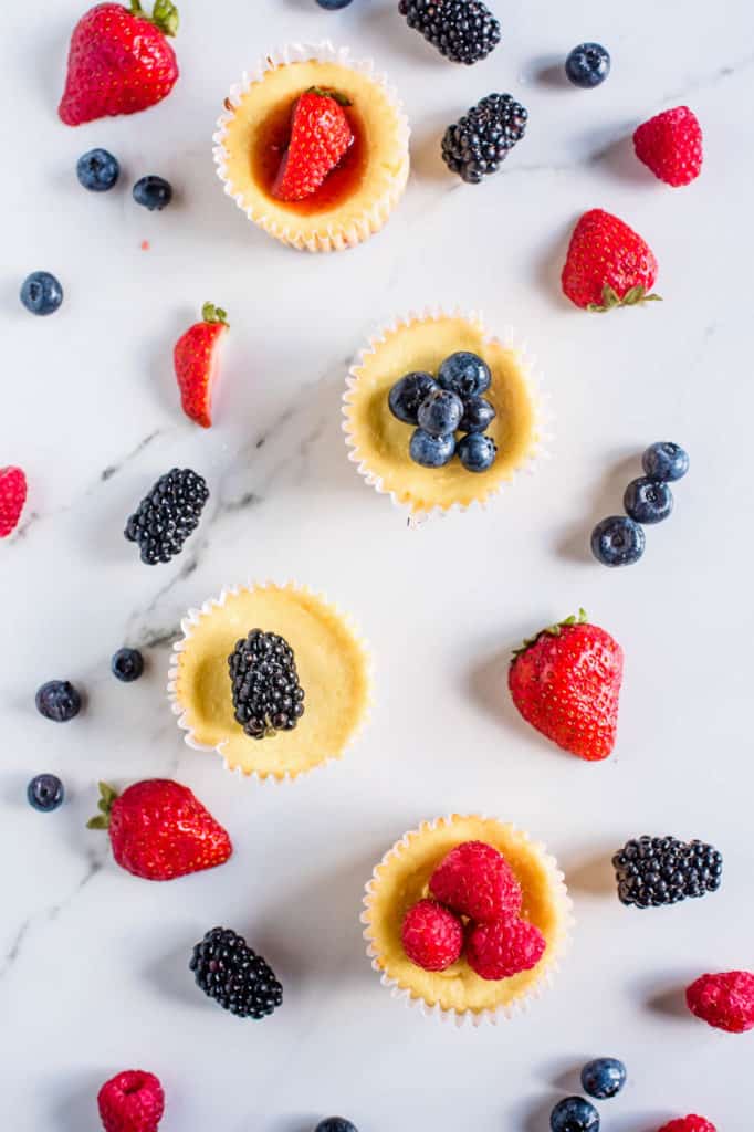 cheesecake bites topped with fresh fruit against a marble background