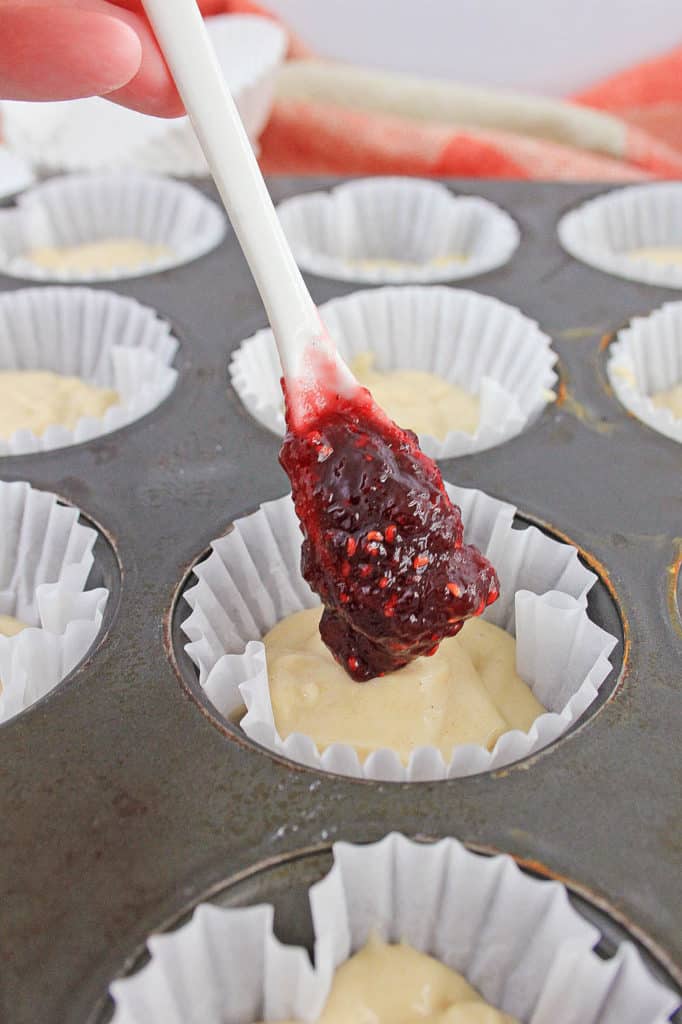 raspberry jam spooned onto the batter in the muffin tin