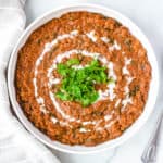 top view of instant pot vegan dal makhani recipe, served in a white bowl with fresh herbs on top