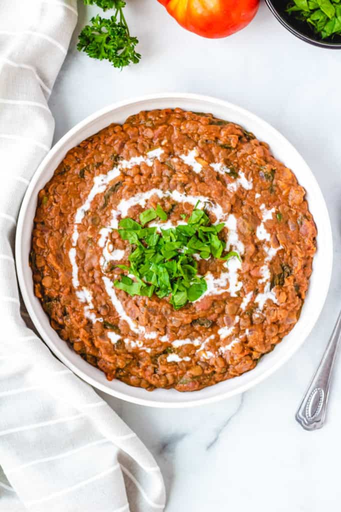 top view of instant pot vegan dal makhani recipe, served in a white bowl with fresh herbs on top
