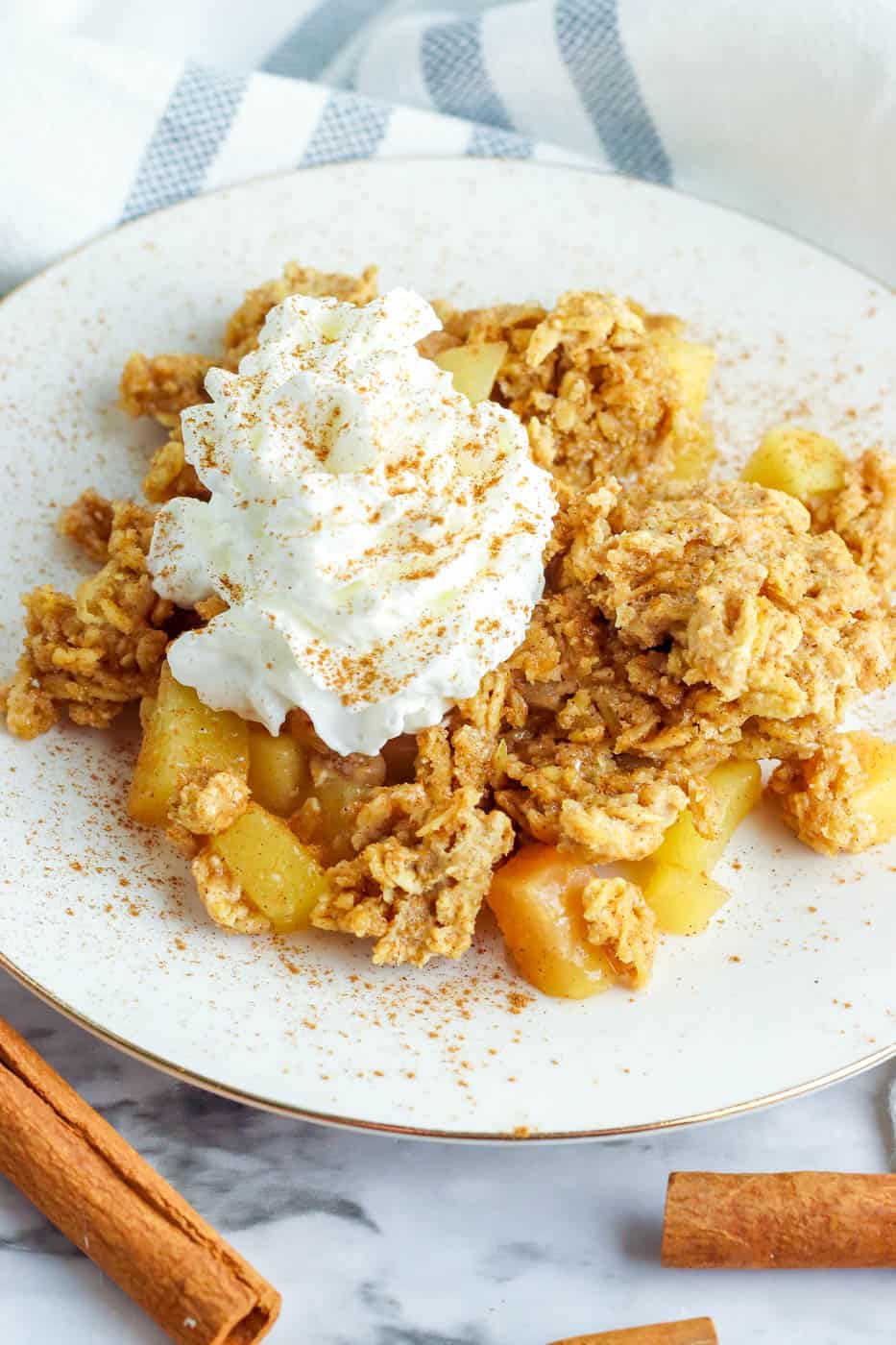 gluten free apple crisp served on a white plate topped with whipped cream