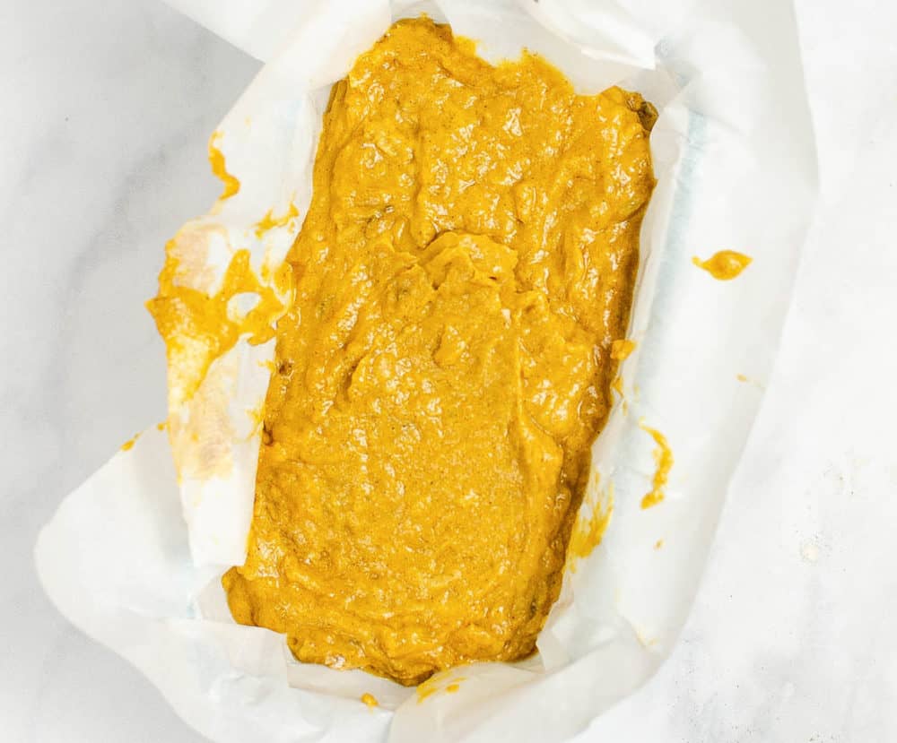 pumpkin bread batter added to a baking dish lined with parchment paper