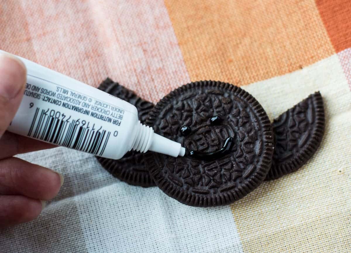 Using gel pen to draw to eyes, and a mouth on an Oreo bat.