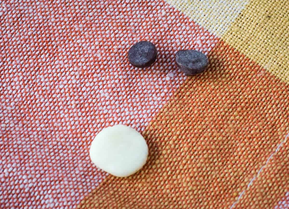 Oreo cream rolled itno a ball and flatted beside two mini chocolate chips.
