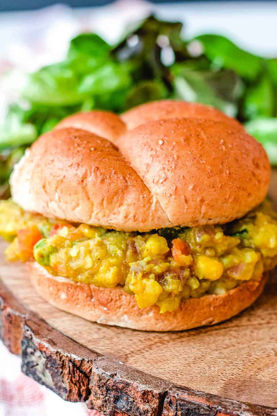 Pav Bhaji (or Indian Spiced Veget، Sloppy Joes) served on a wooden cutting board with a wheat bun