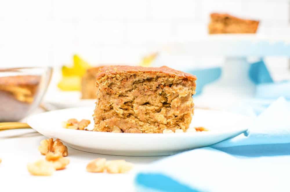 piece of easy vegan banana bread, served on a white plate with a blue napkin in the background