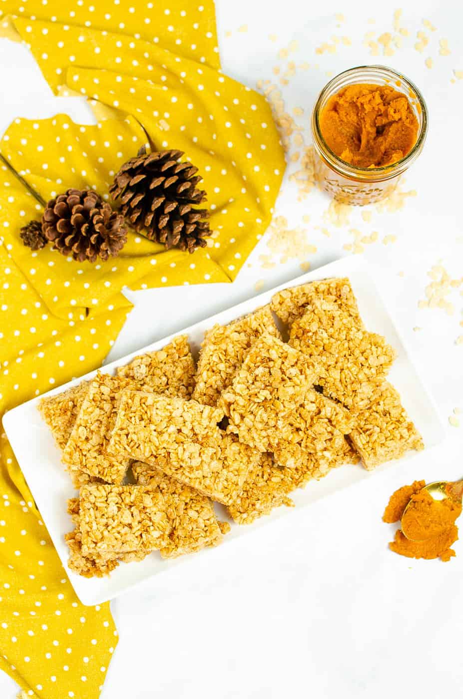 top view of vegan rice krispie pumpkin treats with pumpkin spice on a white platter