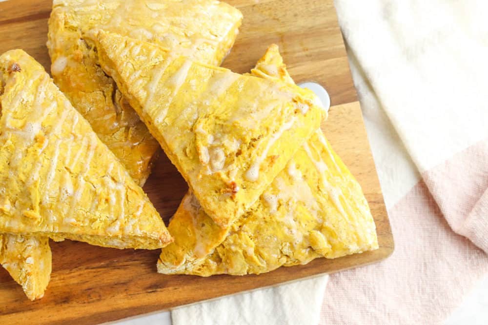 healthy pumpkin scones - vegan scones - on a cutting board, drizzled with a maple glaze