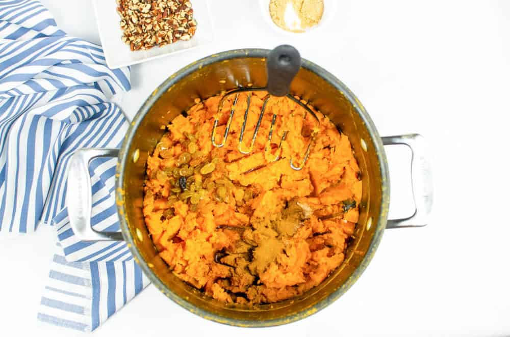 raisins added to sweet potato mash in a pot