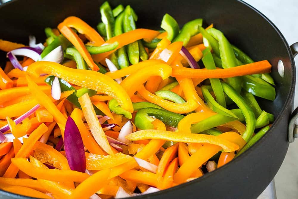 bell peppers and carrots sauteeing in a pan