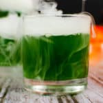 finished shot of green witches brew cocktail served in a square glass