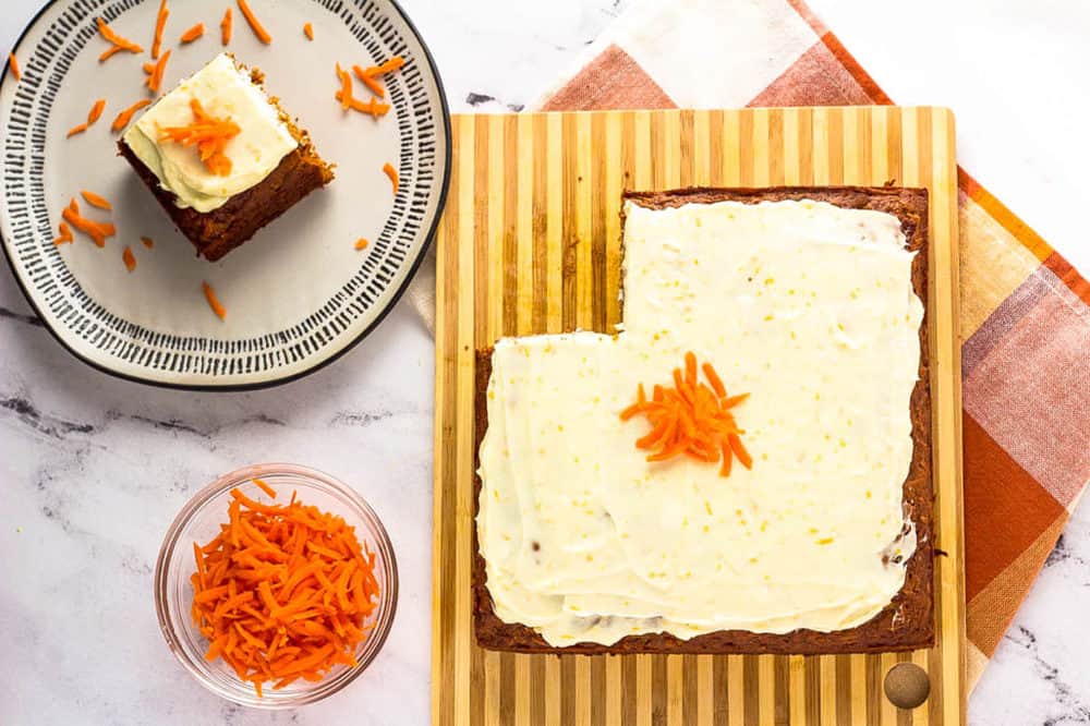 piece of vegan carrot cake with cream cheese frosting on a white plate