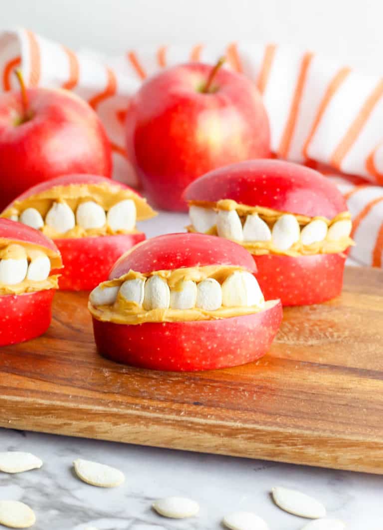 finished funny face halloween apples on a wooden cutting board